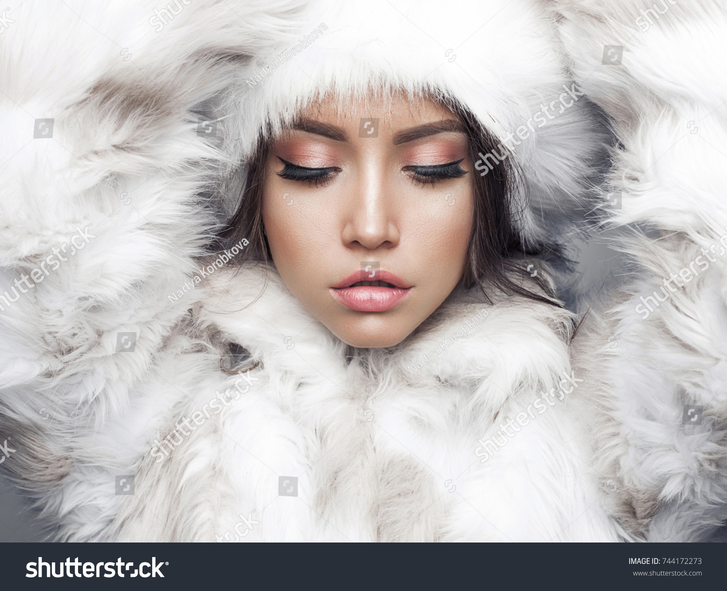 Fashion studio portrait of beautiful lady in white fur coat and fur hat. Winter beauty in luxury. Fashion fur. Beautiful woman in luxury fur coat. Fashion model posing in eco-fur coat and eco-fur hat #744172273