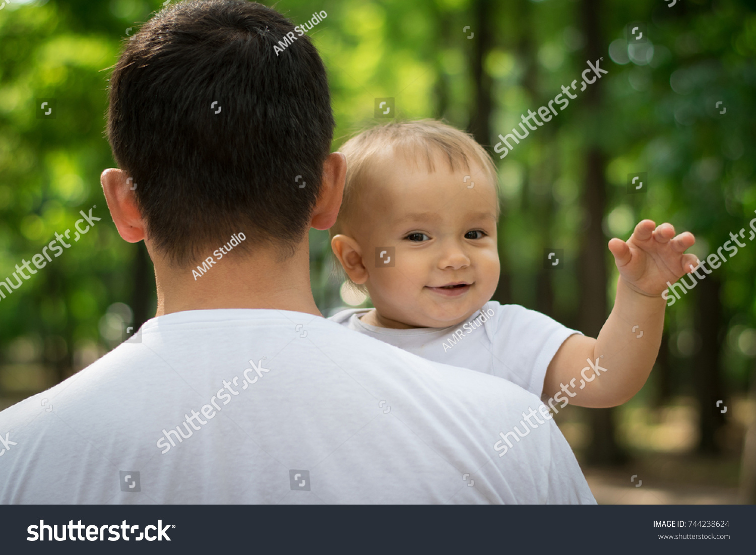 Smiling baby boy waving hand while father holds him in arms. Safe childhood concept #744238624