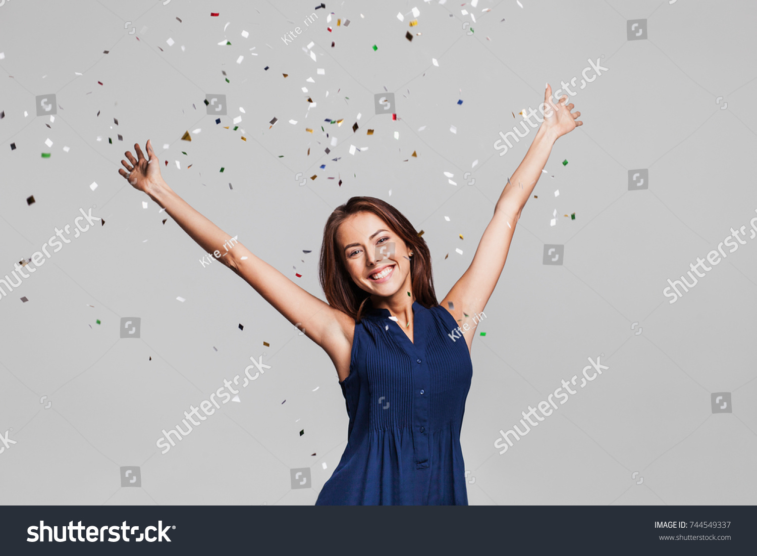 Beautiful happy woman at celebration party with confetti falling everywhere on her. Birthday or New Year eve celebrating concept #744549337