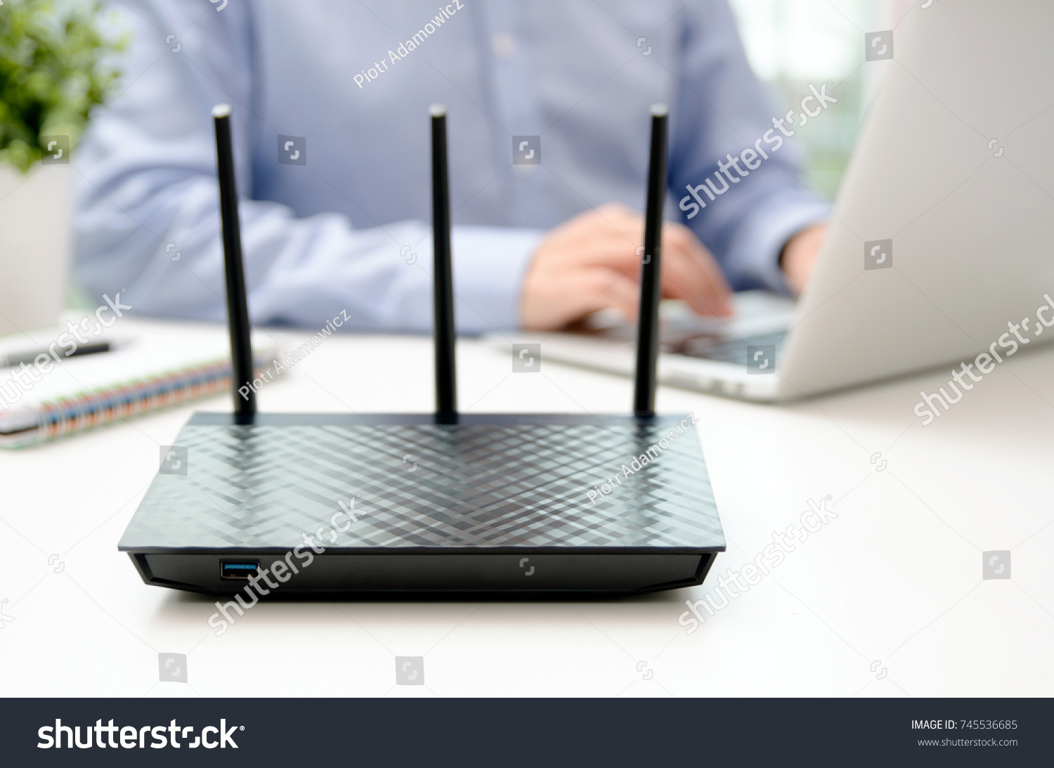 Wireless router and man using a laptop in office. router wireless broadband home laptop computer phone wifi concept #745536685