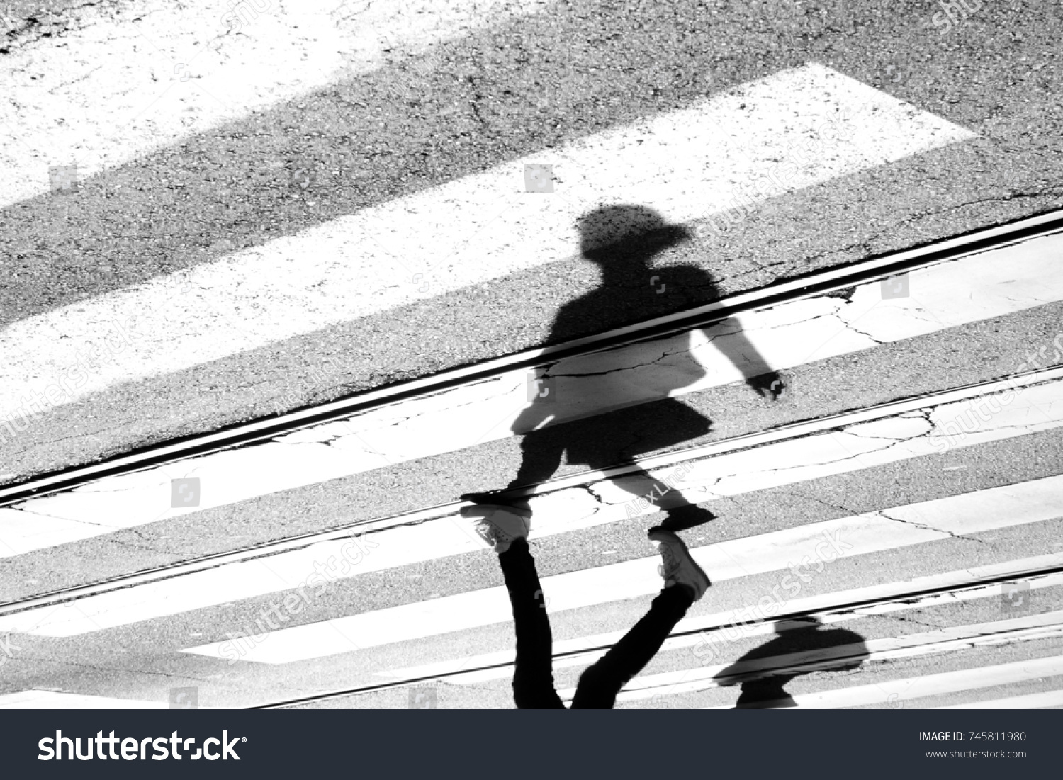 Shadow and silhouette of a teenage girl crossing the street at zebra crosswalk , upside down in black and white #745811980