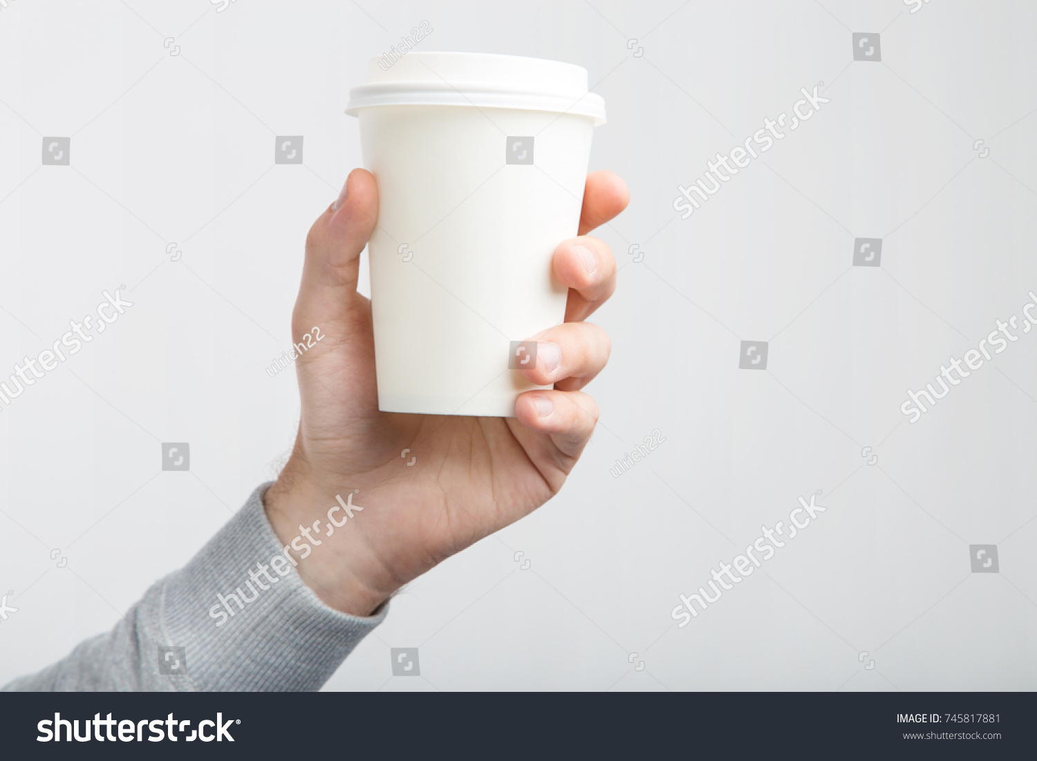 A paper cup of coffee in the hand. White paper cup of coffee in hand. For mock up/ Isolated #745817881