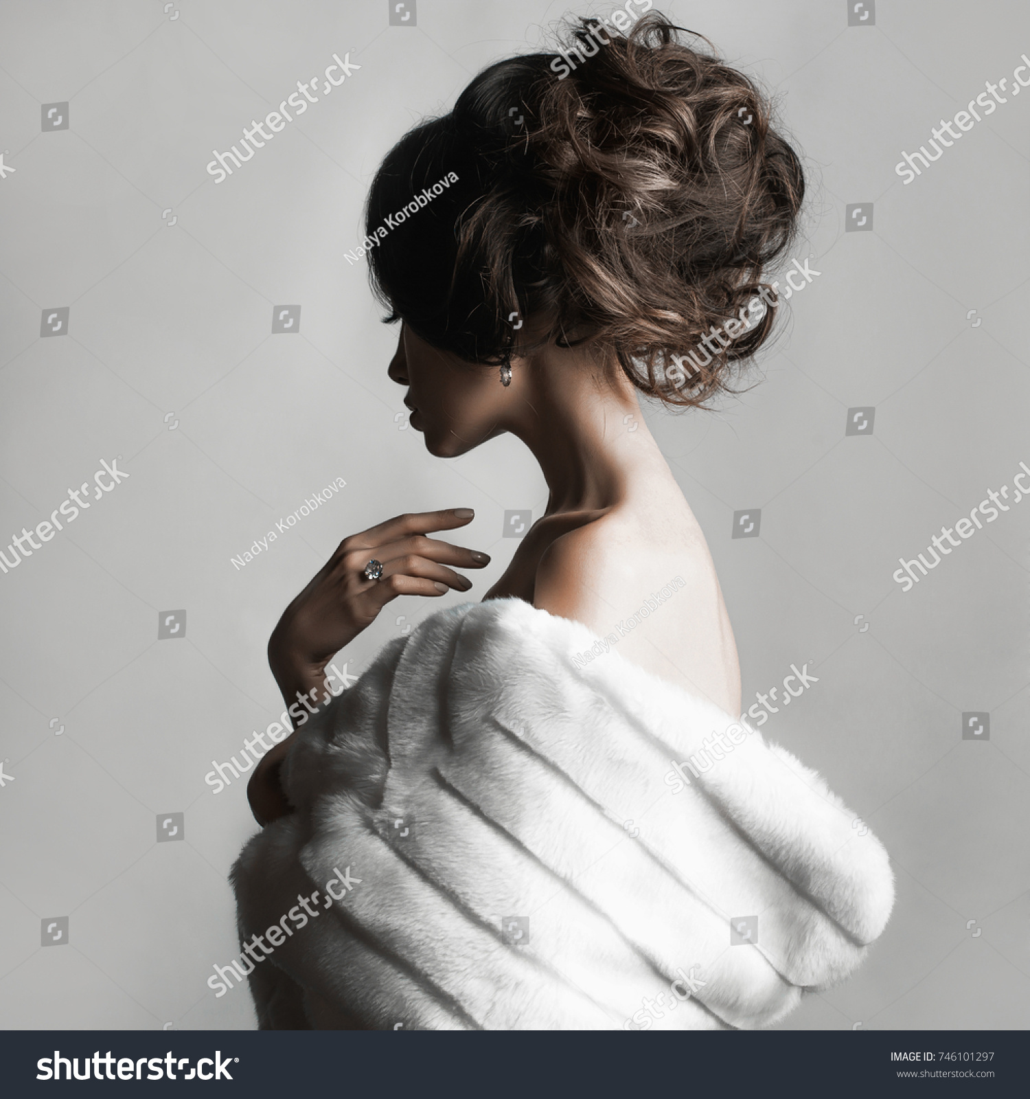 Fashion studio portrait of beautiful lady with elegant hairstyle in white fur coat. Winter beauty in luxury. Fashion fur. Beautiful woman in luxury fur coat. Fashion model posing in eco-fur coat #746101297