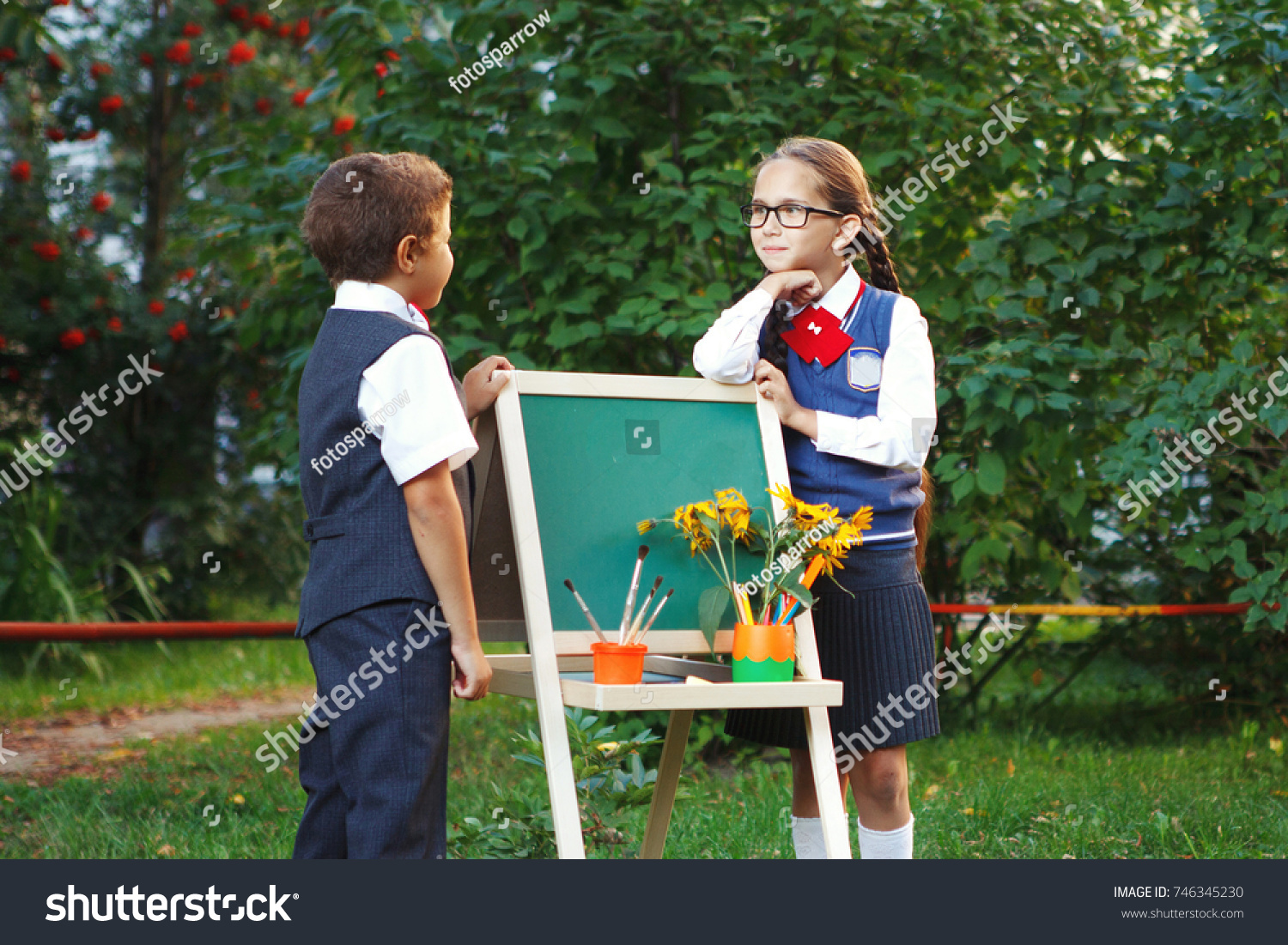 Small pupils a boy and a girl at the blackboard have fun laughing in the Park. copyspace #746345230