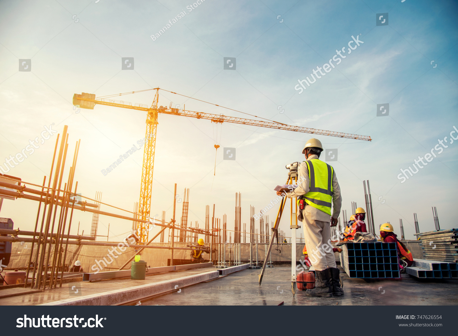 Surveyor builder Engineer with theodolite transit equipment at construction site outdoors during surveying work #747626554