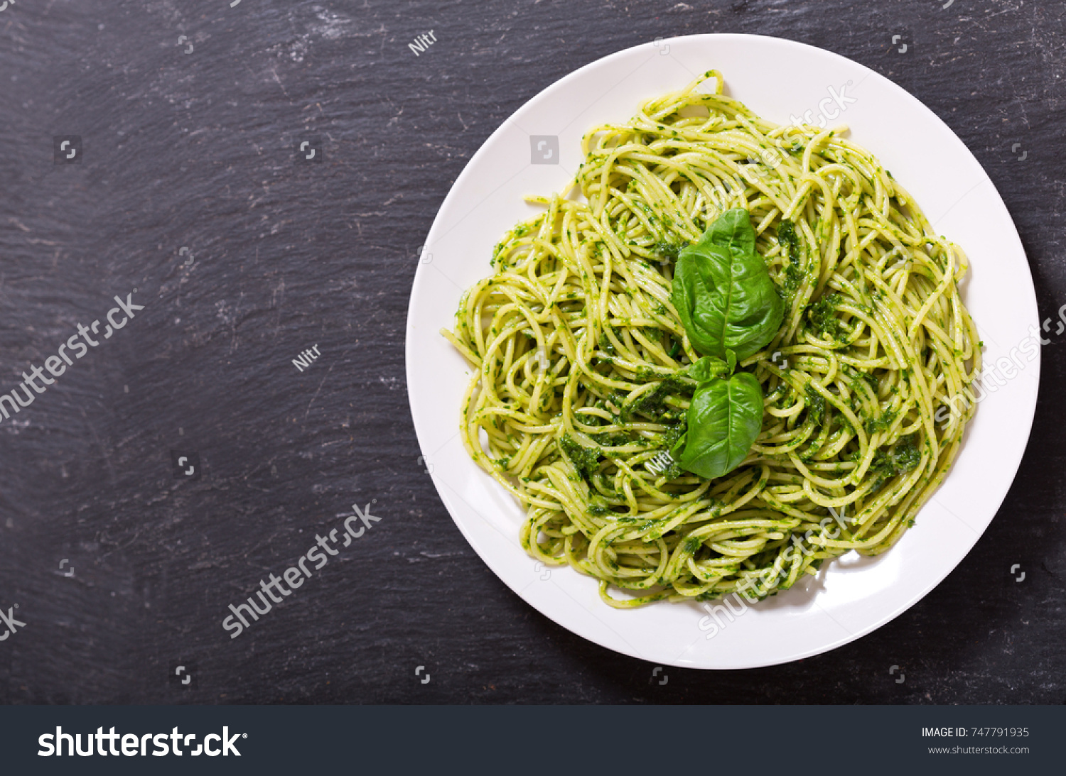 plate of pasta with pesto sauce on dark background, top view #747791935