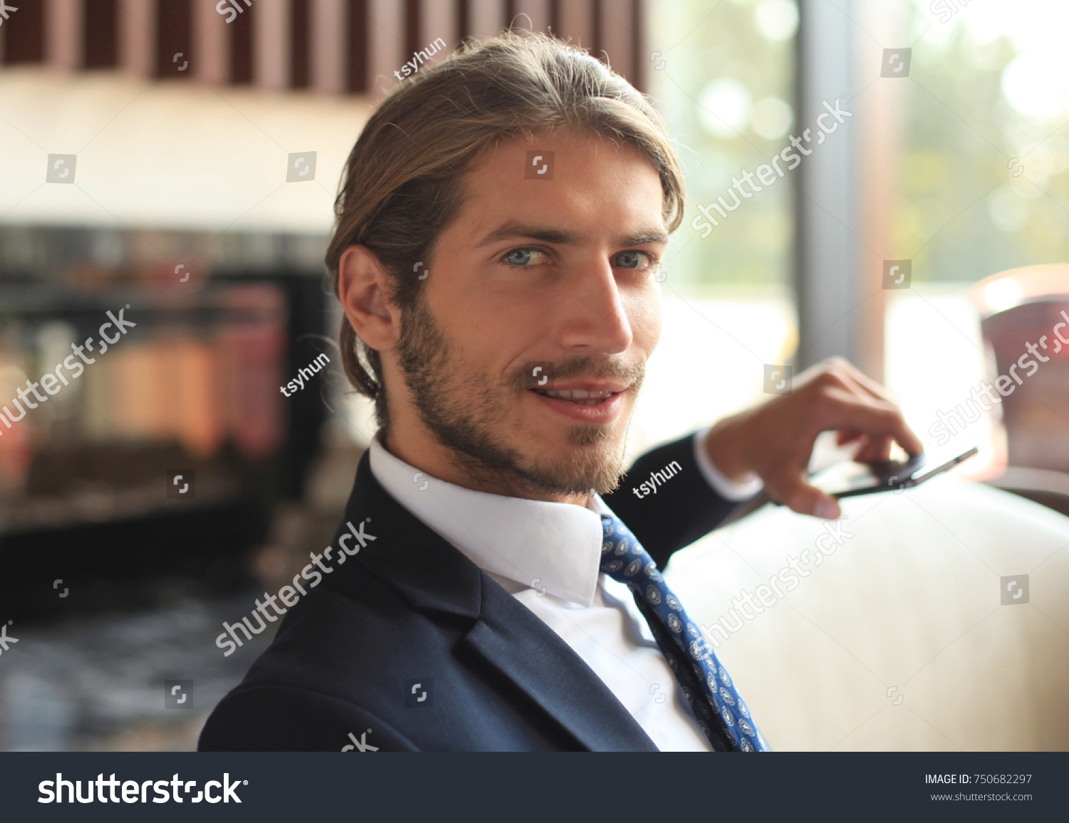 Portrait of happy young businessman sitting on sofa in hotel lobby. #750682297