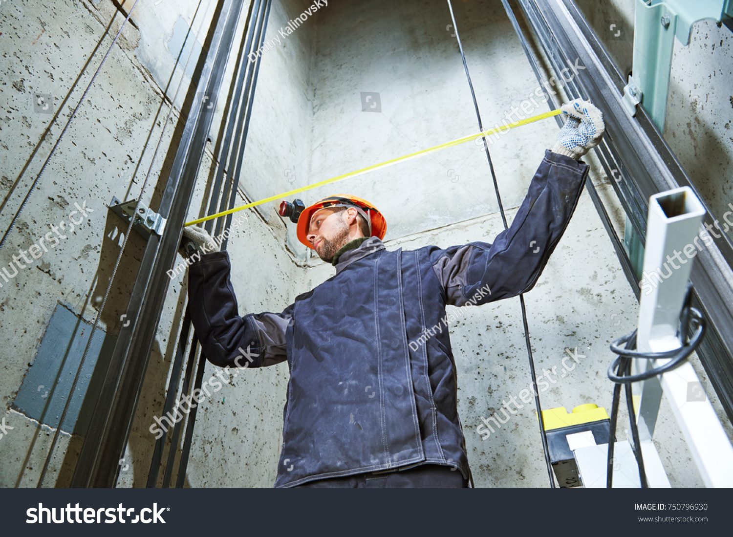 machinist with measure tape checking lift construction in elevator shaft #750796930