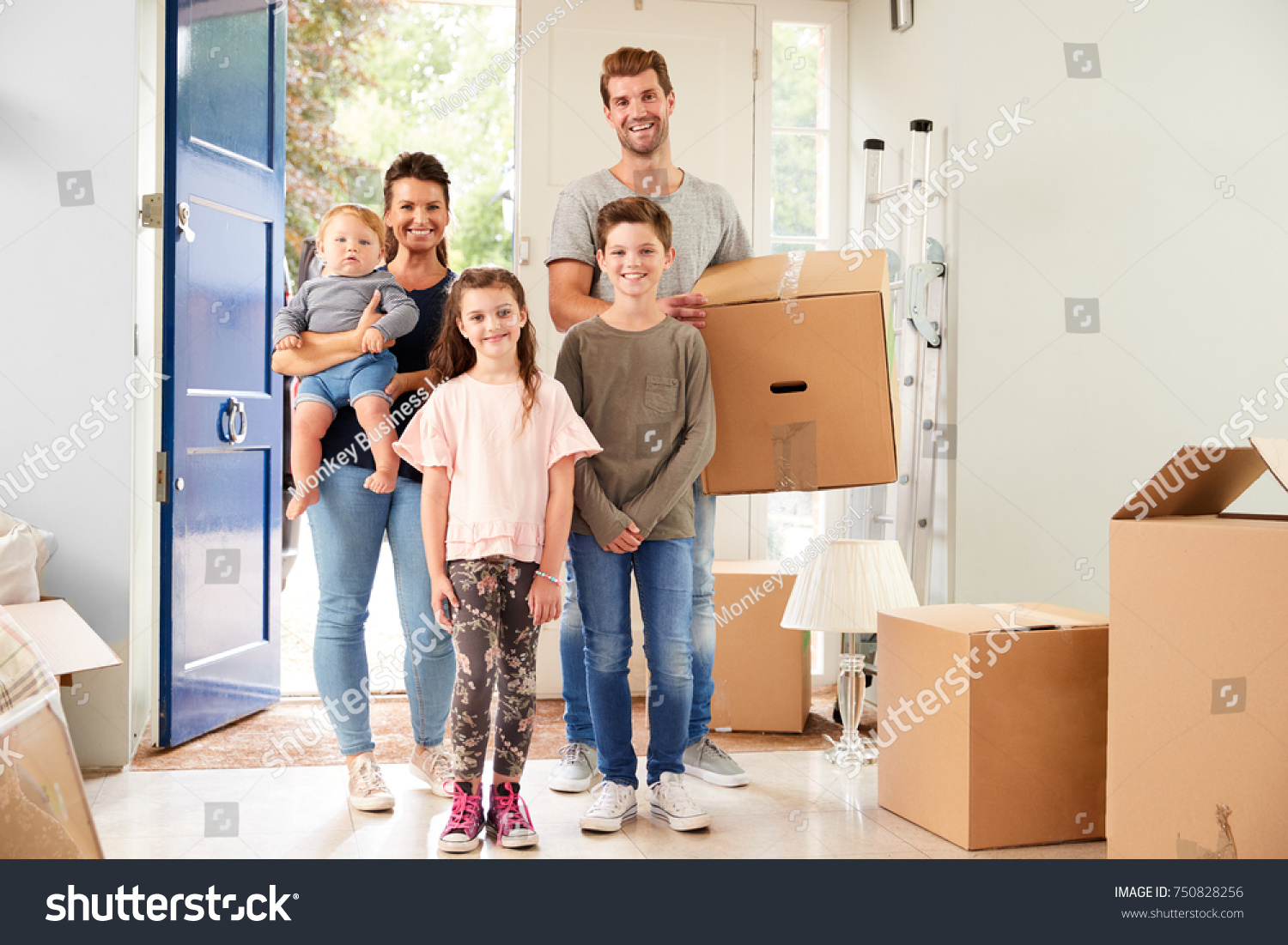 Portrait Of Family Carrying Boxes Into New Home On Moving Day #750828256