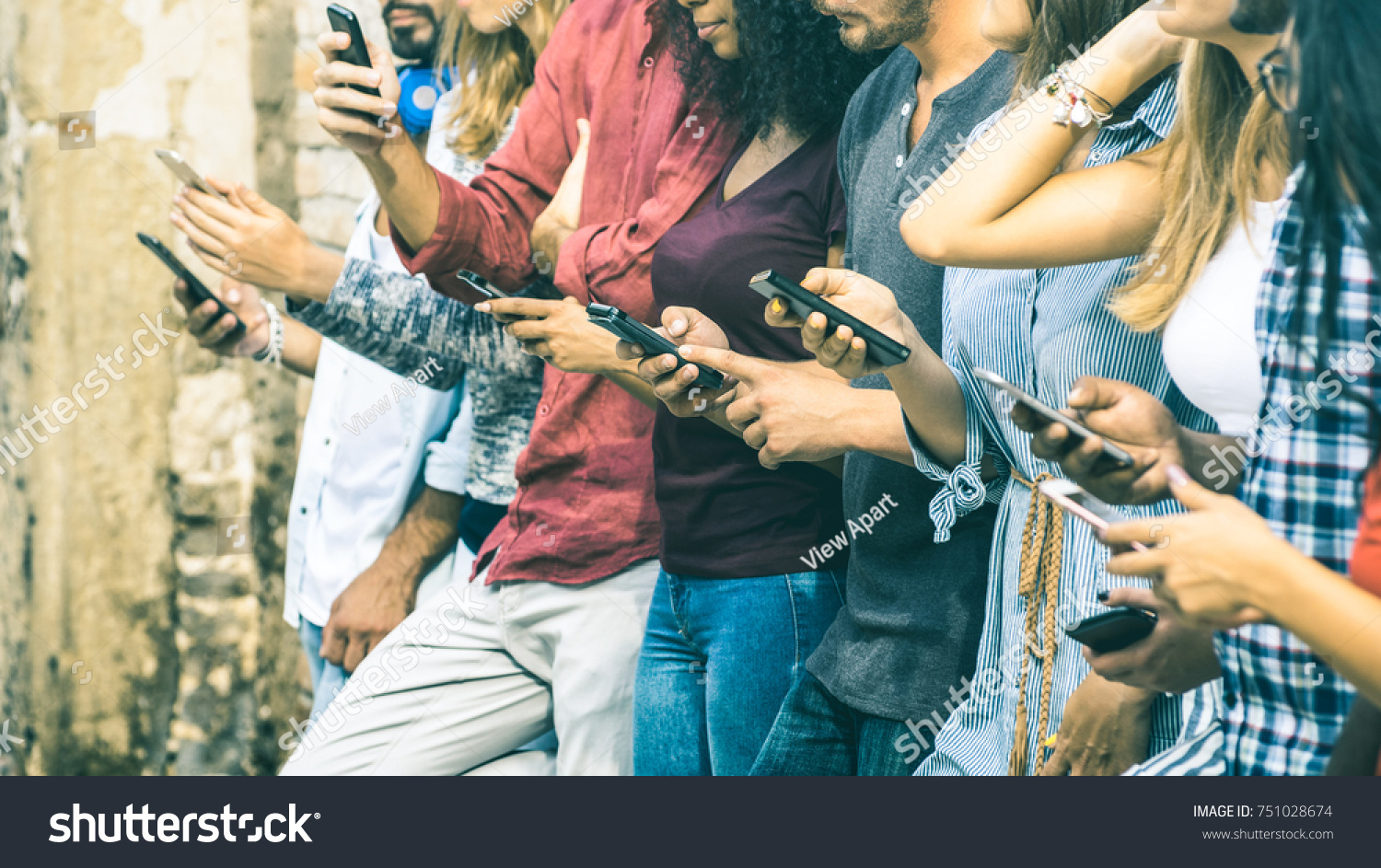 Group of multicultural friends using smartphone outdoors - People hands addicted by mobile smart phone - Technology concept with connected men and women - Shallow depth of field on vintage filter tone #751028674