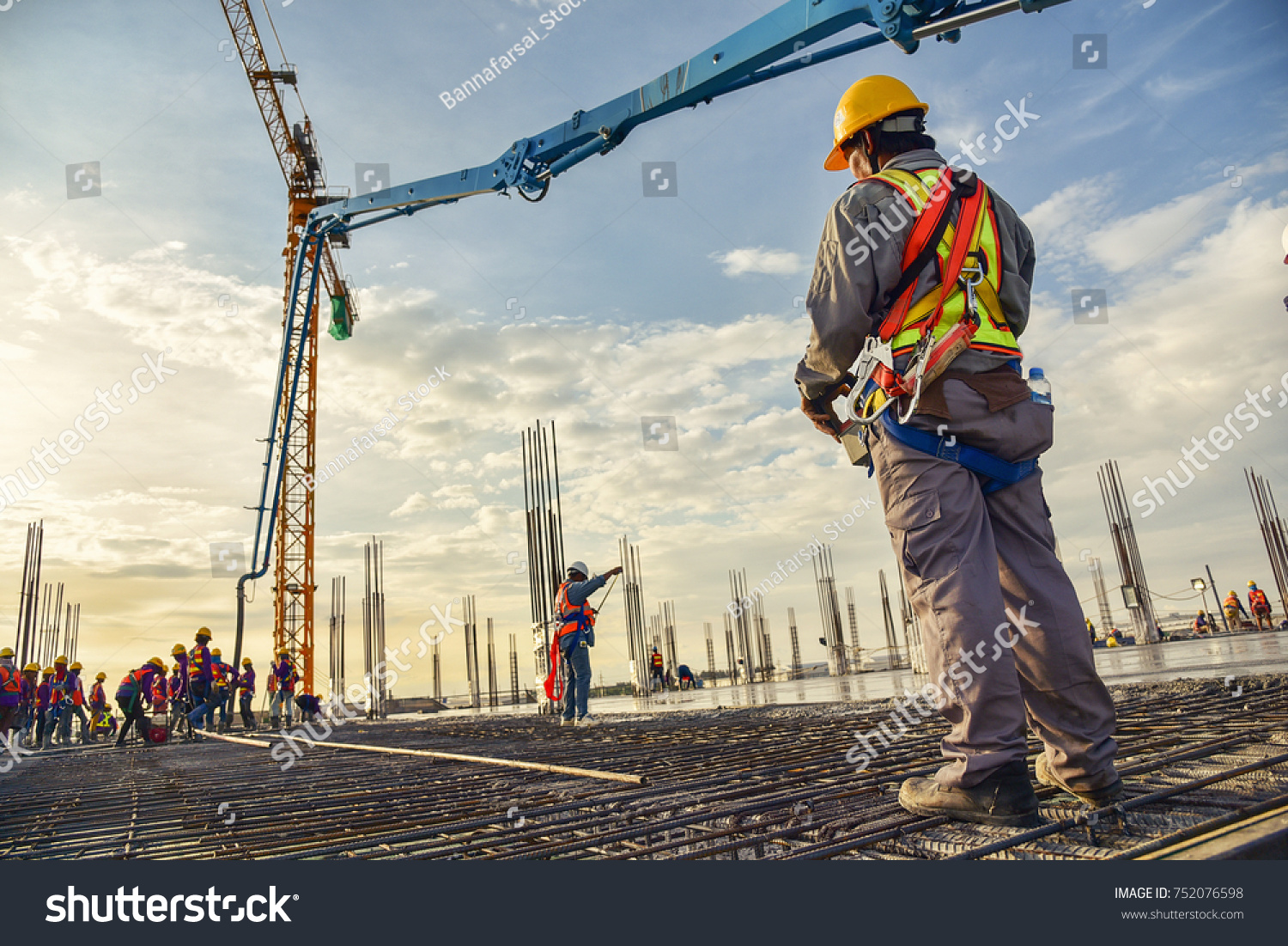 A construction worker control a pouring concrete pump on construction site and sunset background #752076598