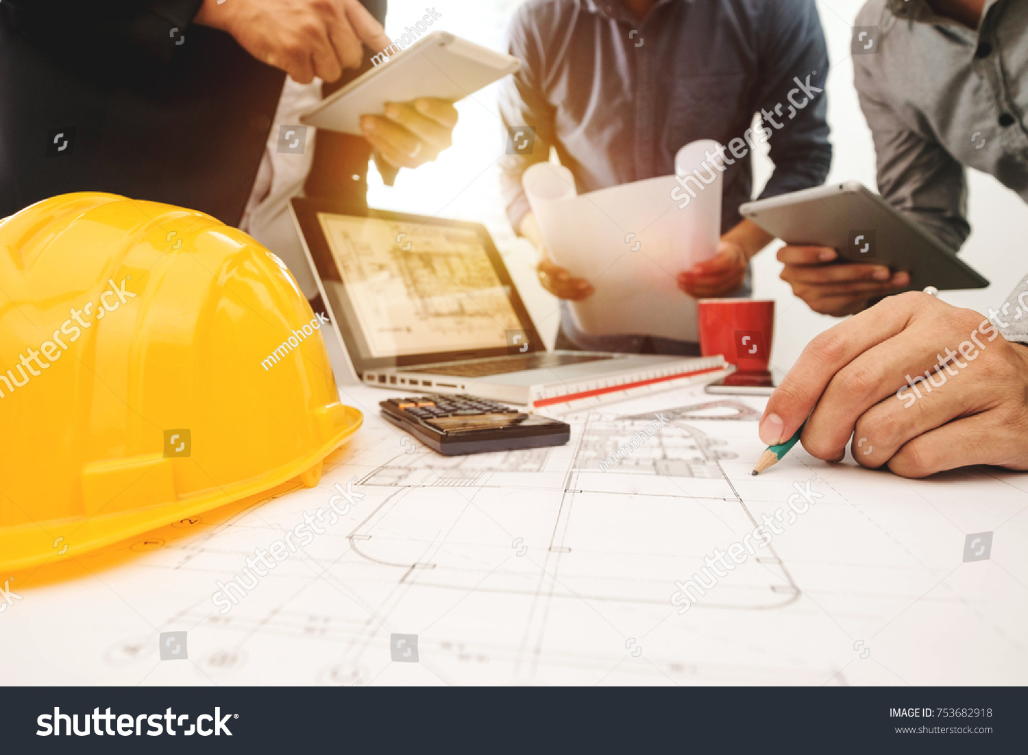 Three colleagues discussing data working and tablet, laptop with on on architectural project at construction site at desk in office
 #753682918