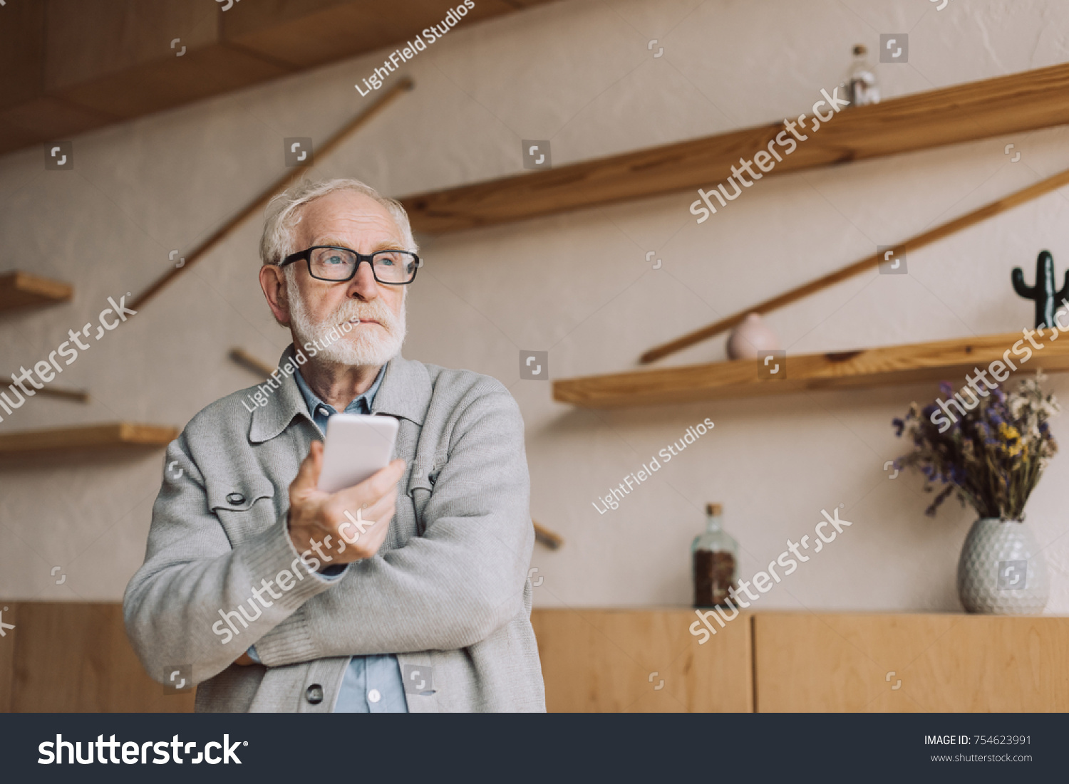 thoughtful senior man with smartphone looking away #754623991