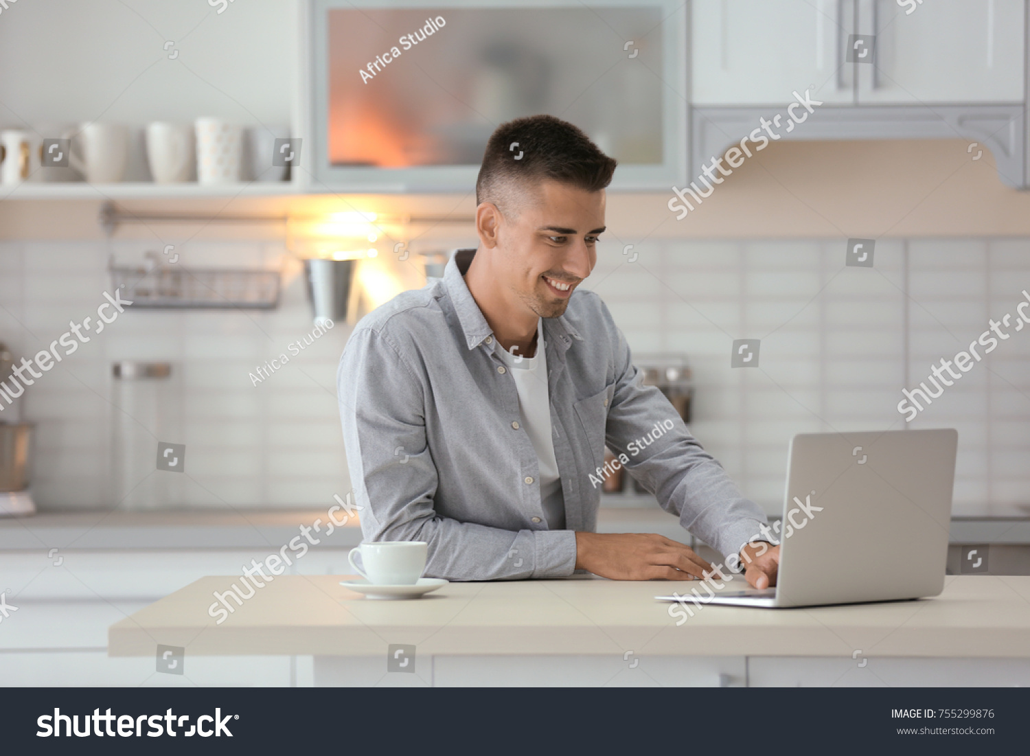 Young man using laptop at table in kitchen #755299876