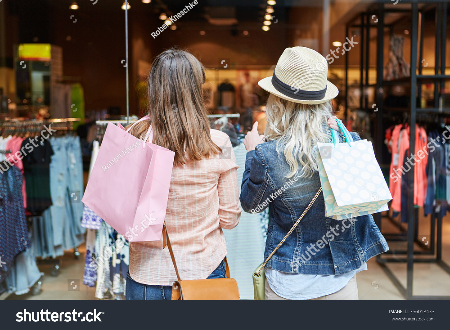 Two women shopping as customers in front of a retail boutique #756018433