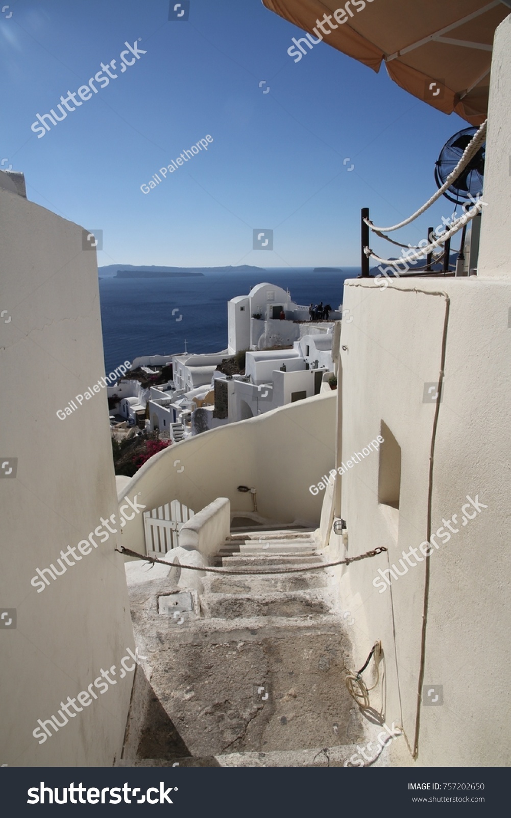 A view of colorful cubiform buildings on Santorini Island in Greece clinging to the cliff over the Aegean Sea.  #757202650