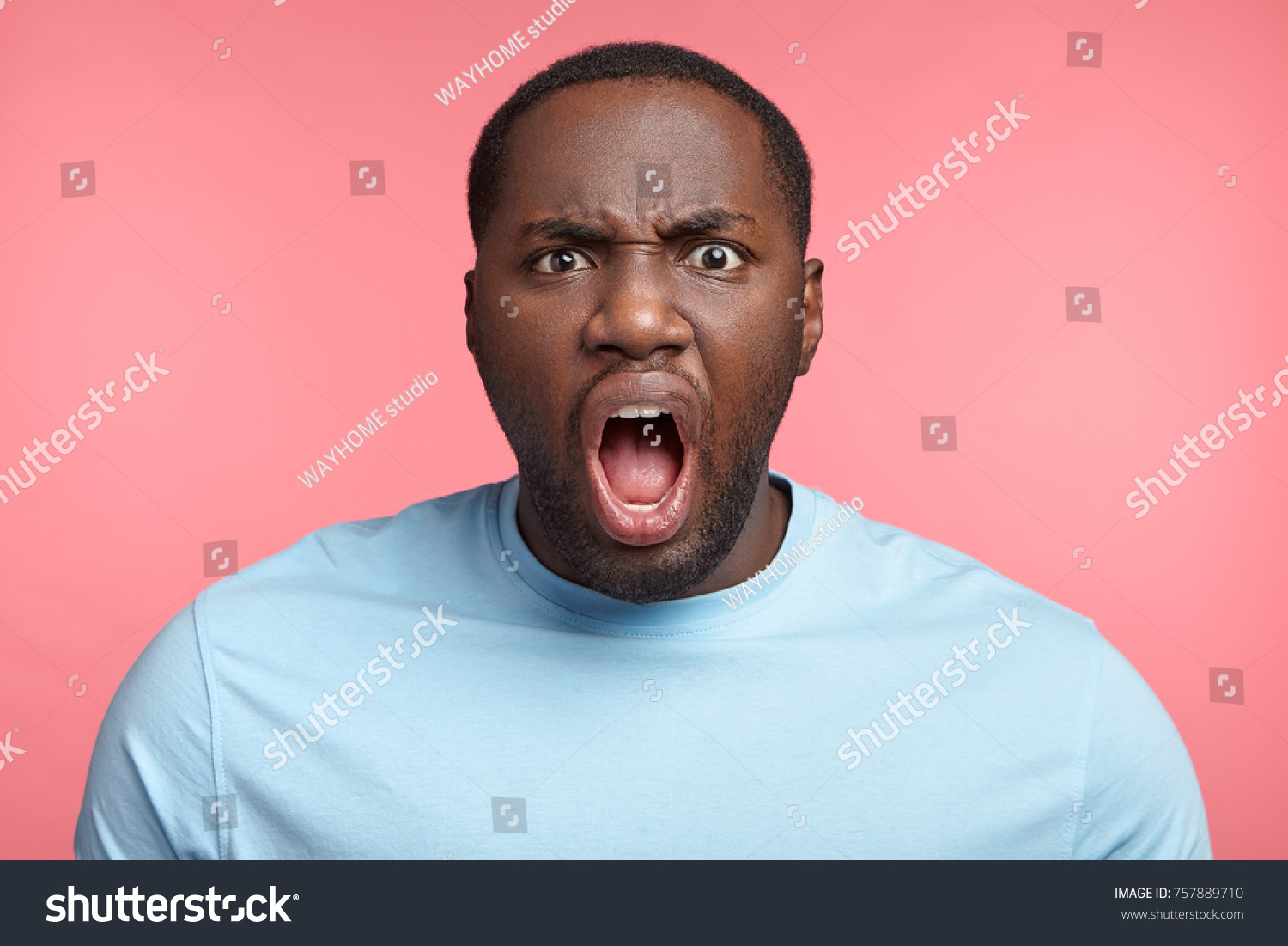 Furious dark skinned male screams loudly, annoyed with interlocutor, expresses negative emotions and feelings, keeps mouth widely opened. Angry African boss shouts at coworkers, being strict #757889710