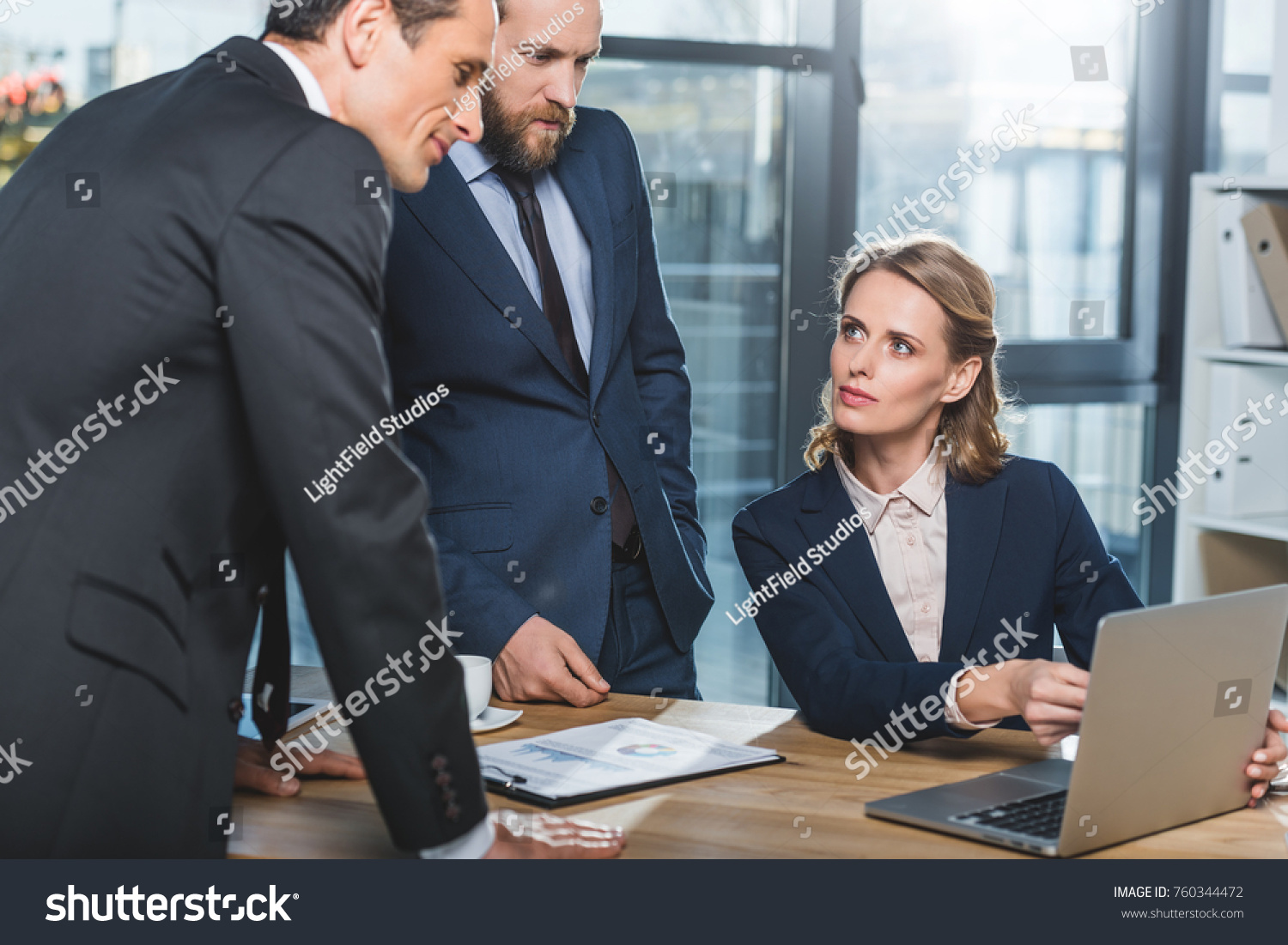 portrait of concentrated lawyers using laptop together during work in office #760344472