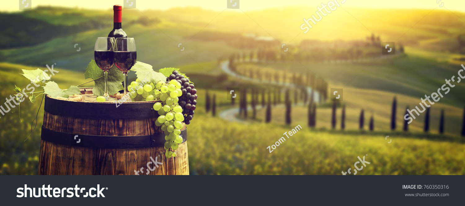 Red wine bottle and wine glass on wodden barrel. Beautiful Tuscany background #760350316