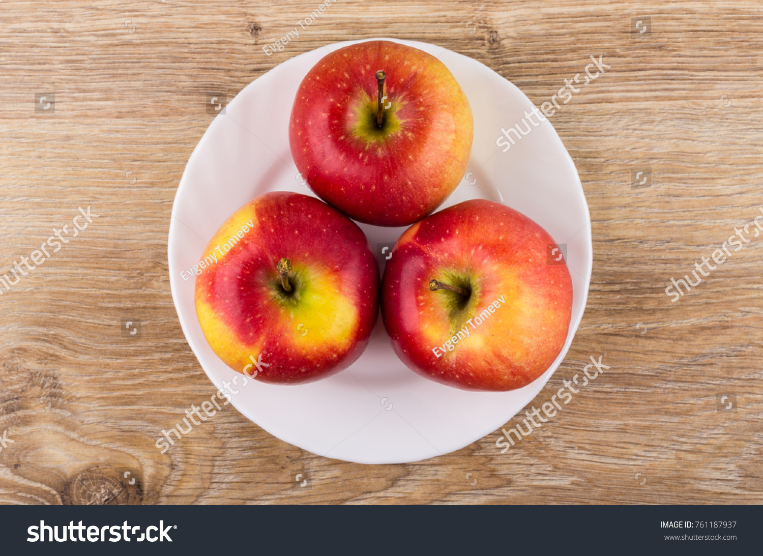 Ripe red apples in white dish on wooden table. Top view #761187937