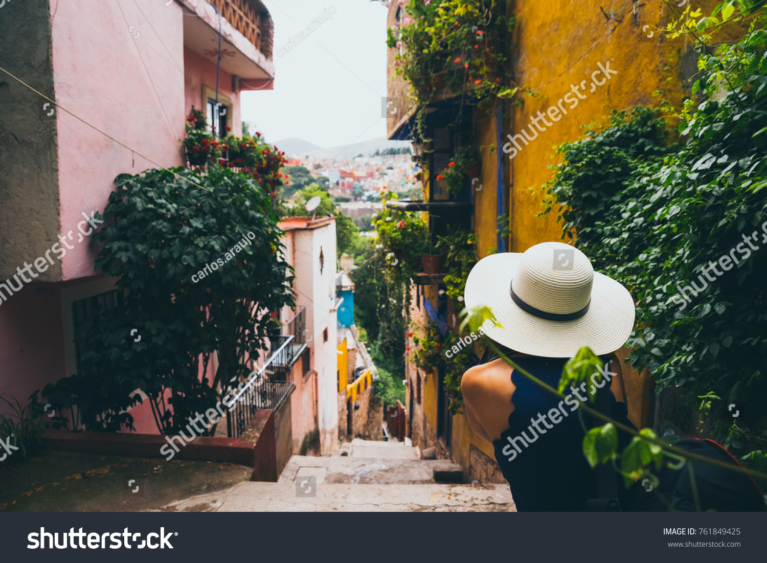 Woman with a hat sitting in a Guanajuato alley enjoying the view of the town #761849425