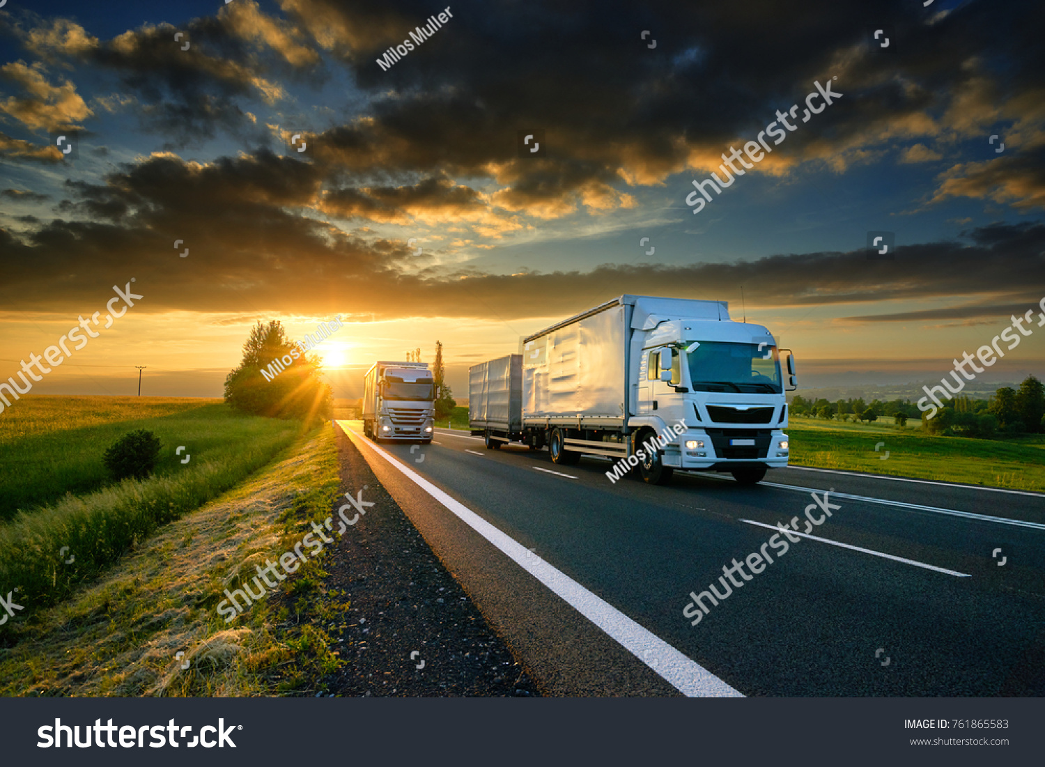 Overtaking trucks on an asphalt road in a rural landscape at sunset #761865583