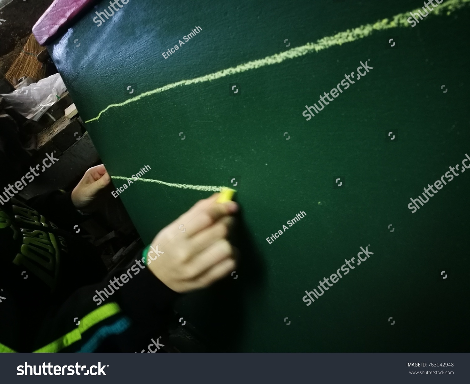 School life. A pupil is lining on a chalkboard. Yellow chalk is in use. Writing lession. Lines. #763042948