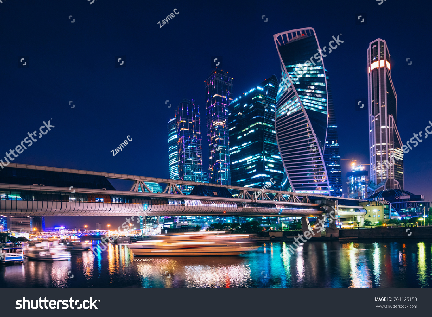 Business center with skyscrapers of Moscow-city at night under the blue sky and with reflections of the illumination on the water. Cityscape #764125153