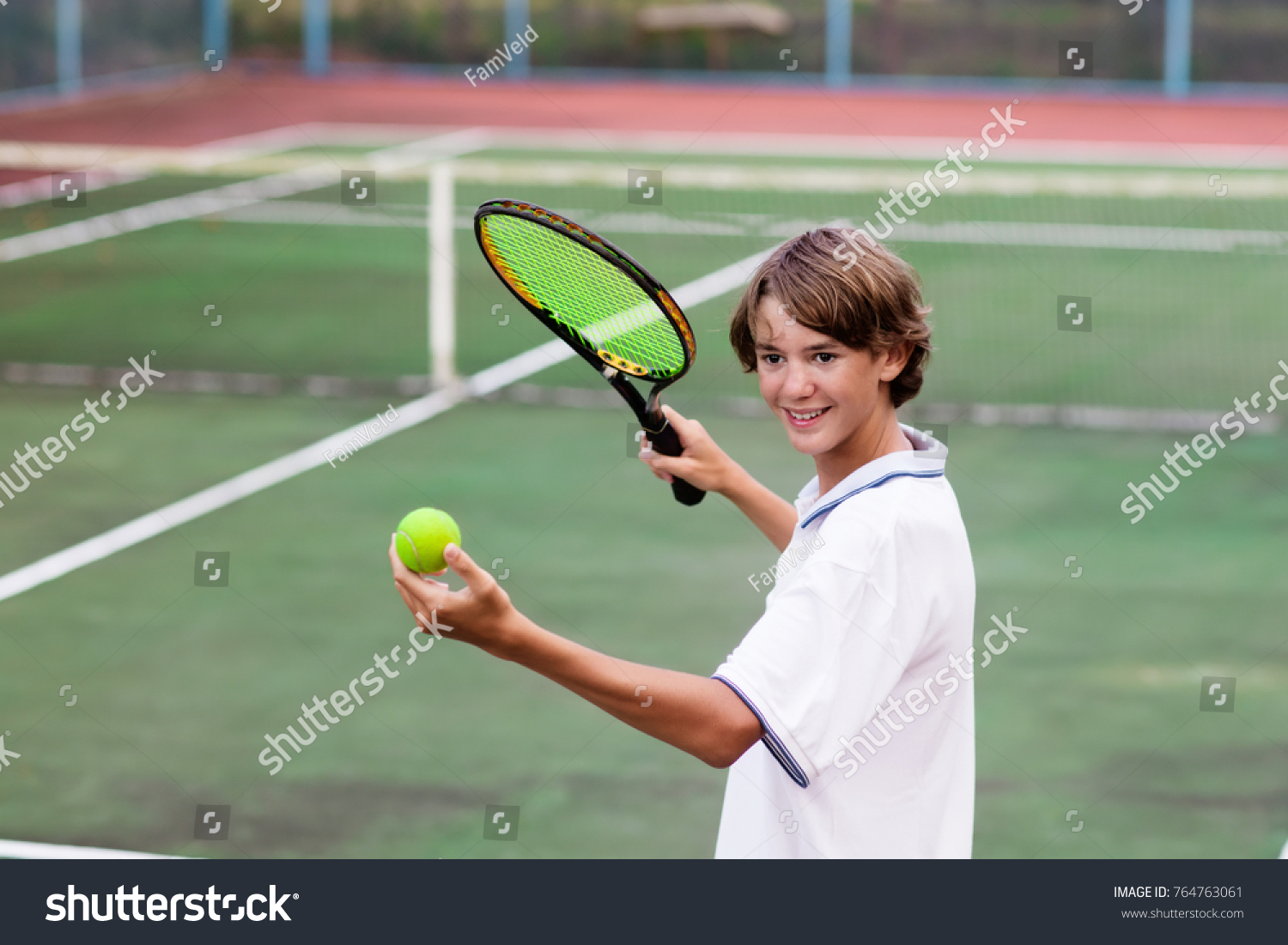 Boy playing tennis on outdoor court. Teenager with tennis racket and ball in sport club. Active exercise for kids. Summer activities for children. Training for young kid. Child learning to play. #764763061