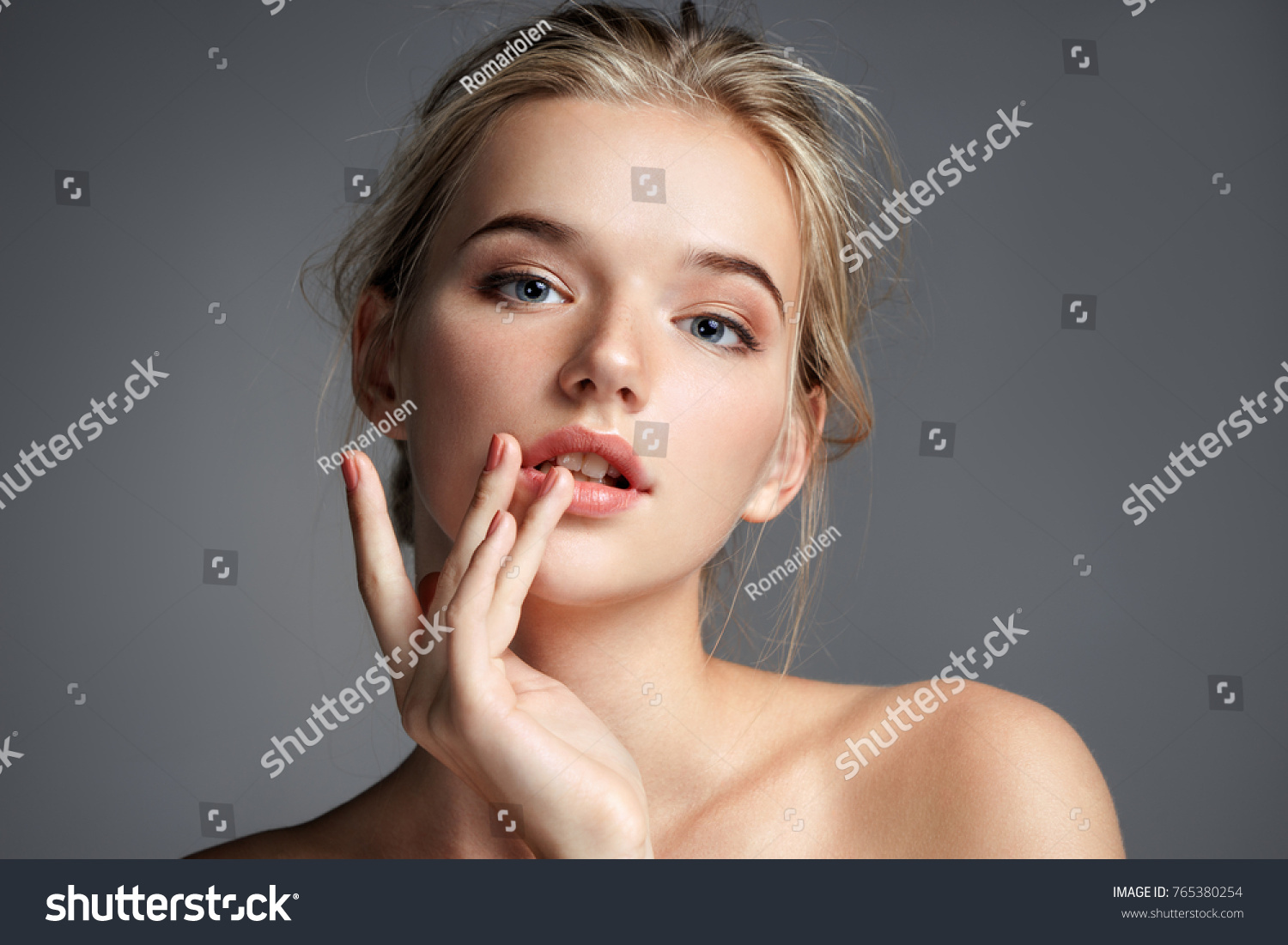 Image with beautiful blonde girl touching her lips on grey background. Beauty & Skin care concept #765380254