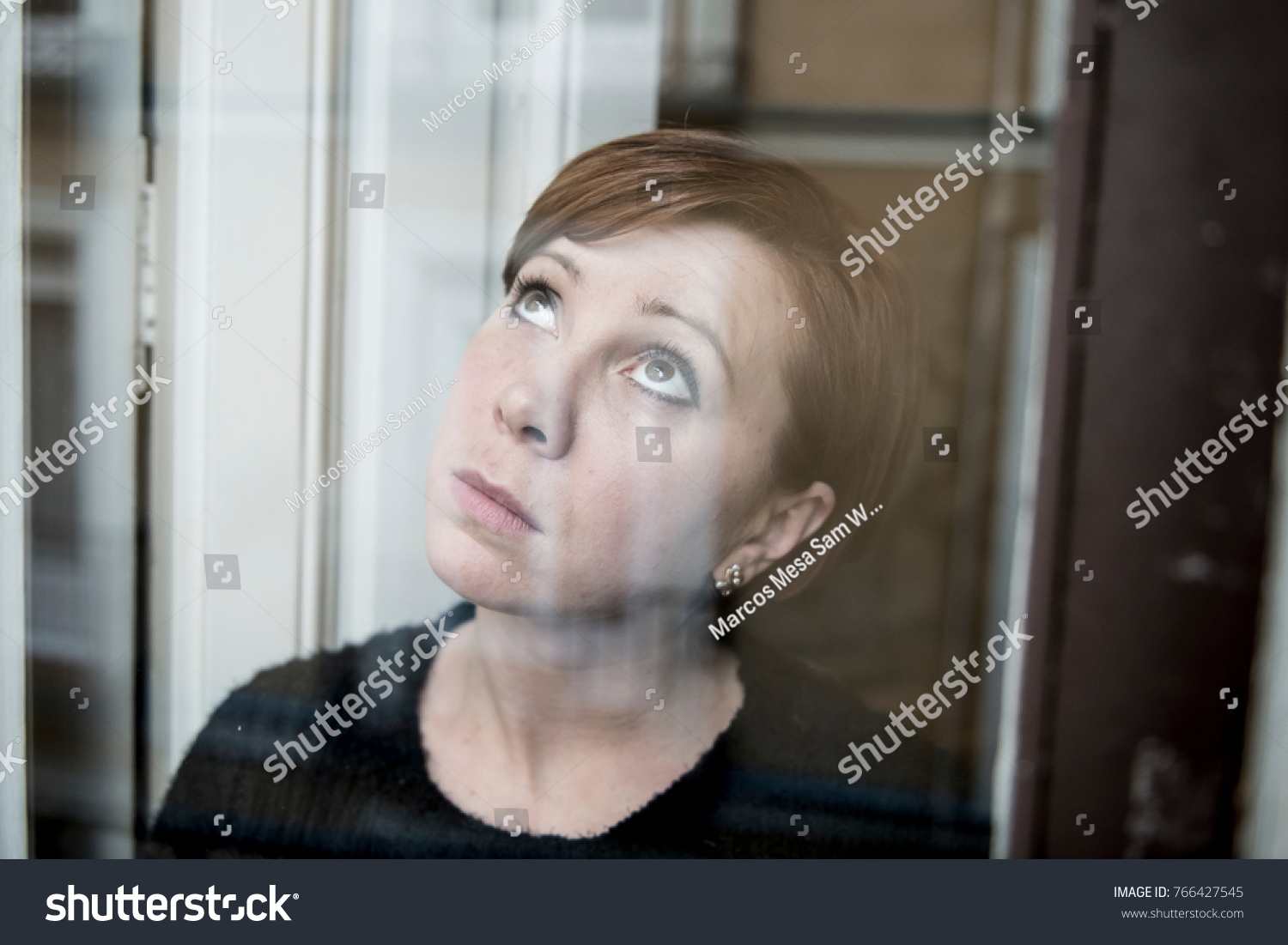 dramatic close up portrait of young beautiful woman thinking and  feeling sad suffering depression at home window looking depressed and worried in lifestyle and life problems concept #766427545