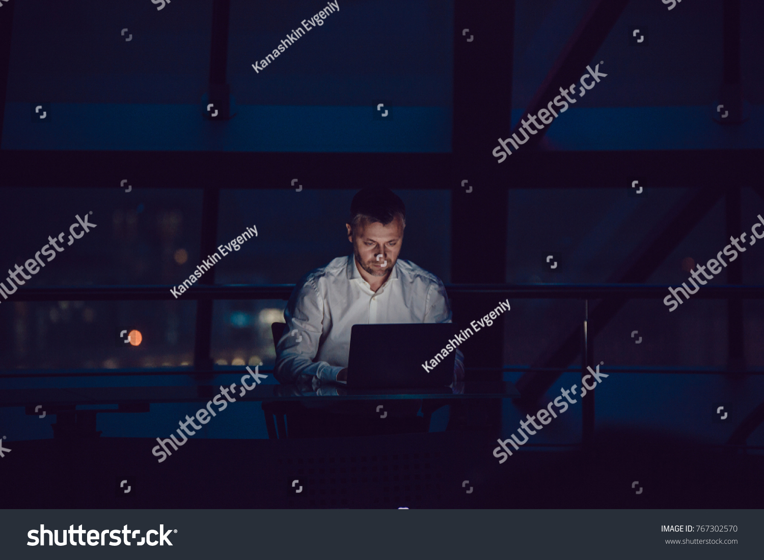 Businessman working on laptop in night office. #767302570