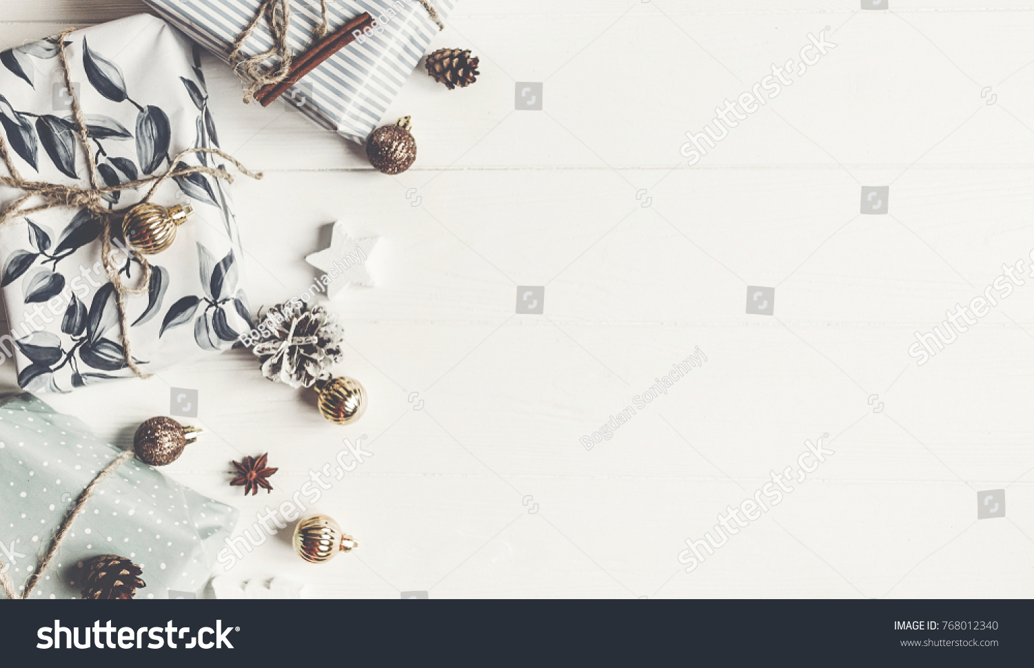 modern christmas flat lay. wrapped presents with ornaments and pine cones anise on rustic white wooden background top view, space for text. stylish gifts. seasonal greetings. happy holidays #768012340