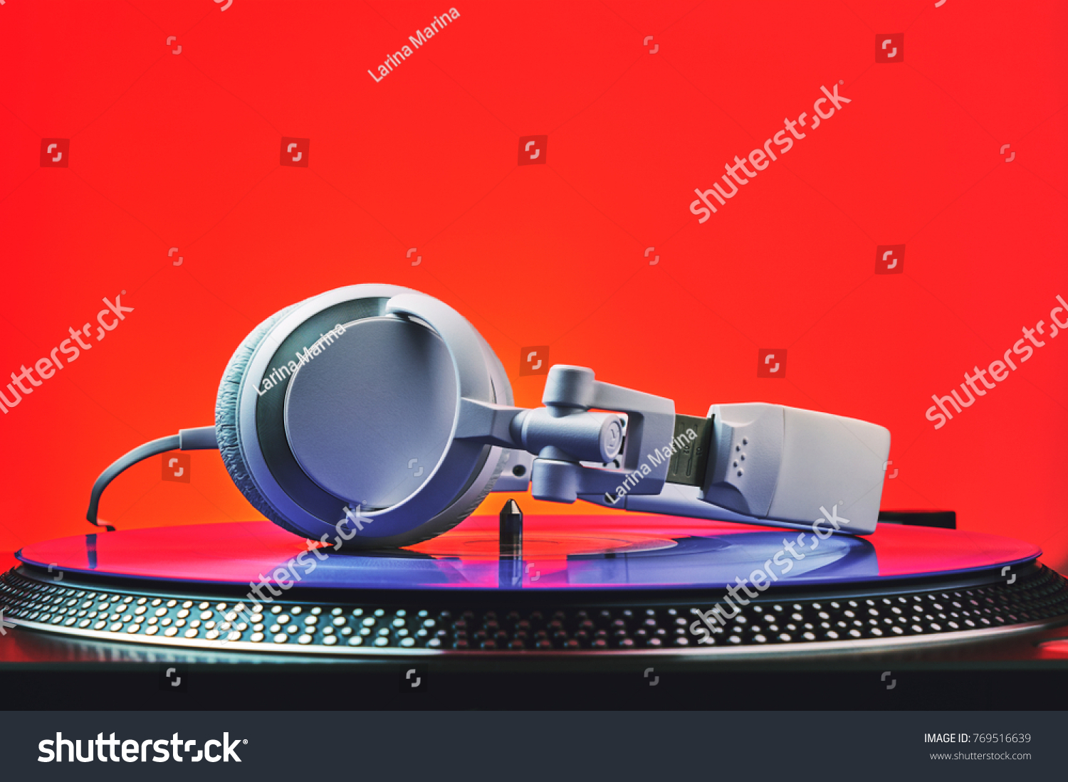 Player turntable vinyl records and white headphones in red light. Equipment for the disc jockey. Sound technology for DJ to mix and play music. Violet vinyl plate. Vinyl turntable in red light #769516639