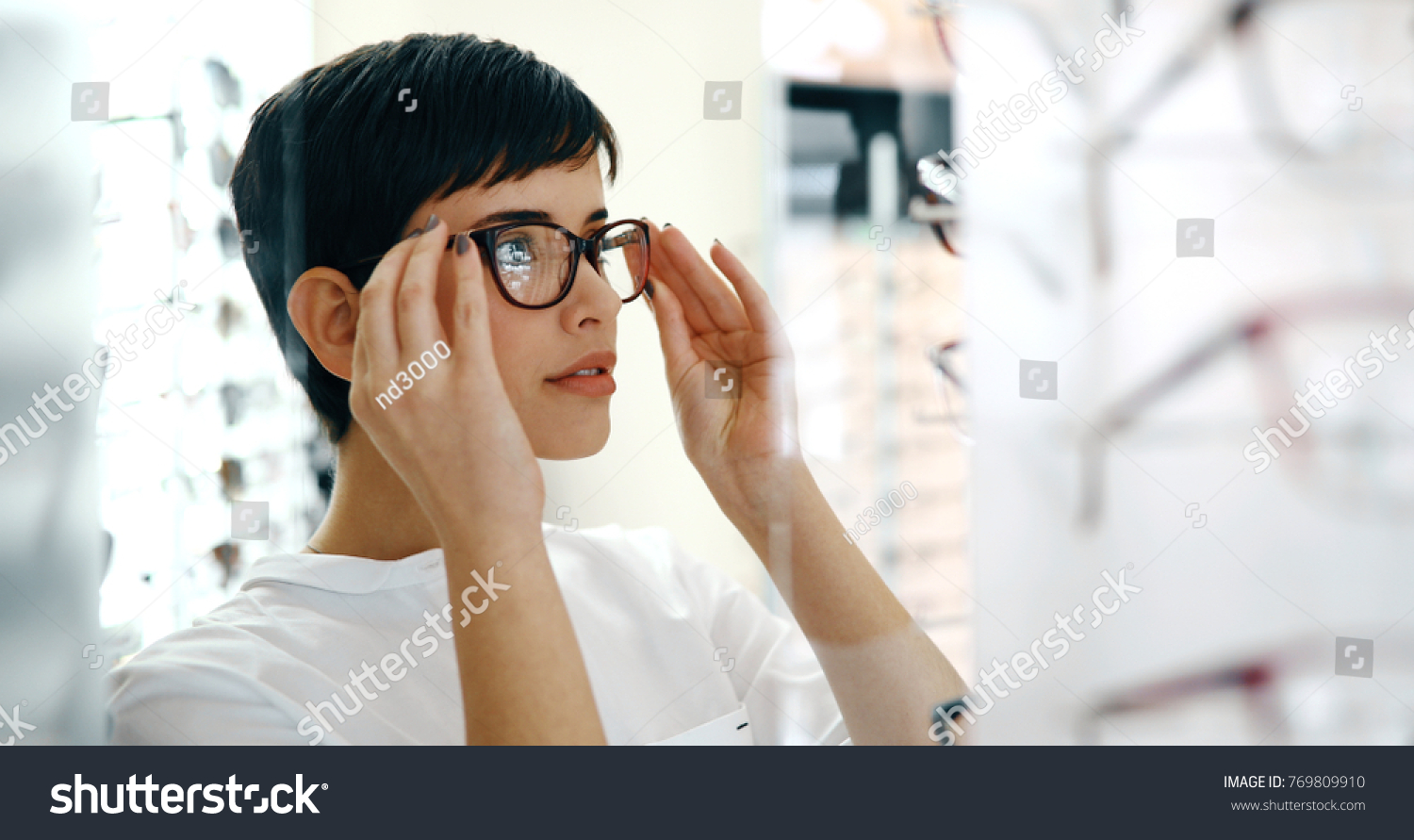 health care, eyesight and vision concept - happy woman choosing glasses at optics store #769809910