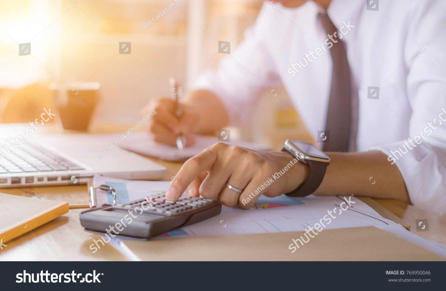 Businessman accountant using calculator and laptop for calculating finance on desk office. business financial accounting concept. #769950046