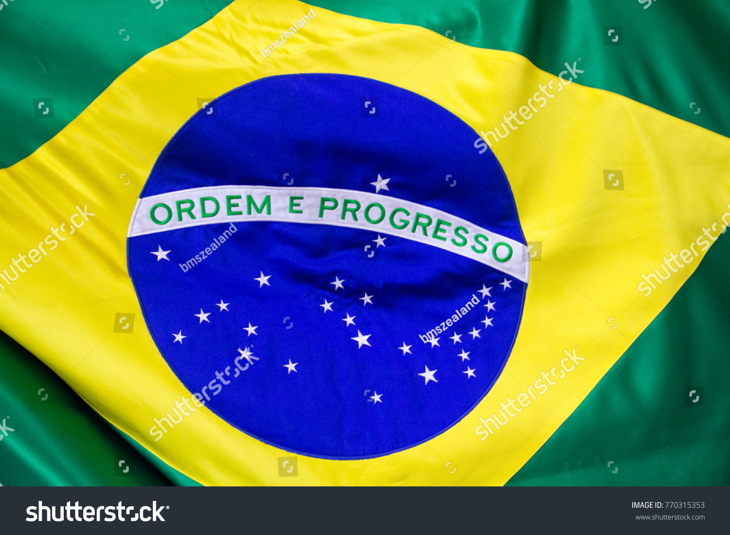 The Brazilian flag in fabric, with a close up of the blue disc depicting a starry sky  spanned by the national motto "Ordem e Progresso"  ("Order and Progress"), within a yellow rhombus, on green.  #770315353