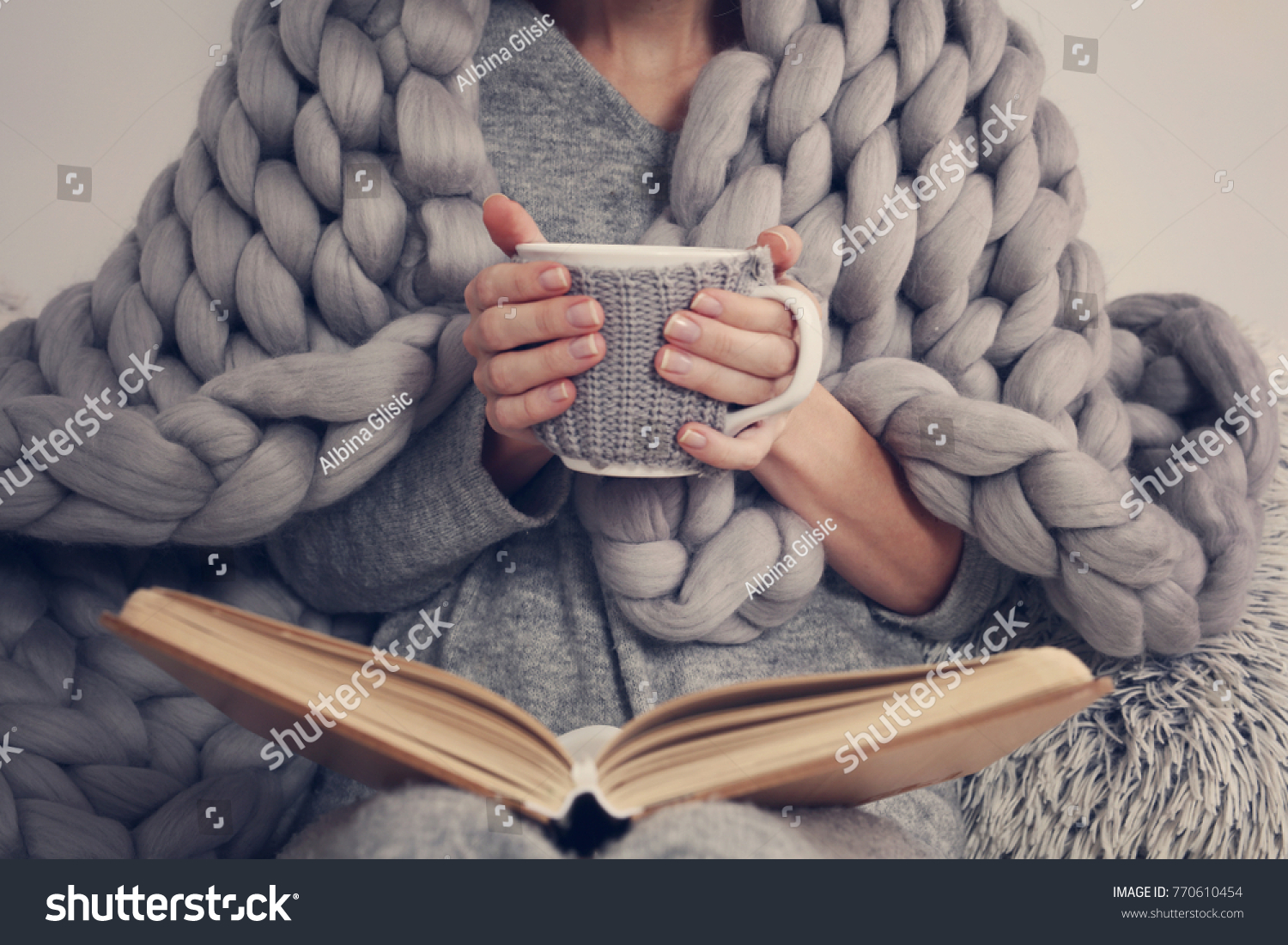 Cozy Woman covered with warm soft merino wool blanket reading a book. Relax, comfort lifestyle. #770610454