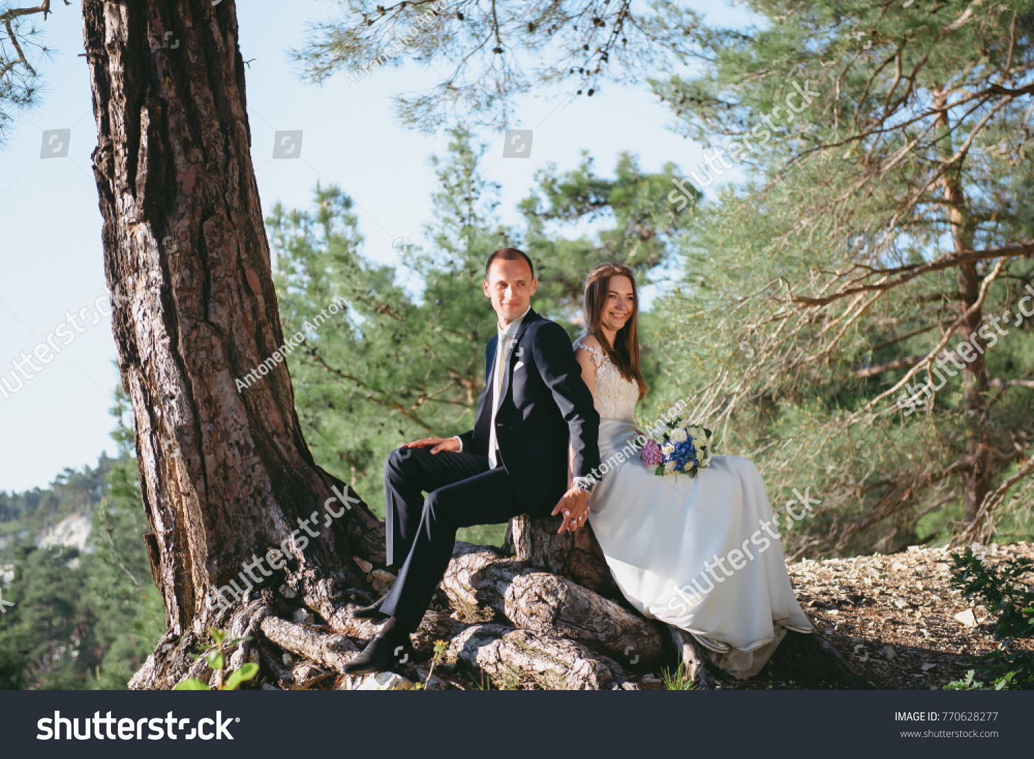 Beautiful young couple honeymooning in the forest hugging and holding hands. The enamored married girl hugs her husband. #770628277