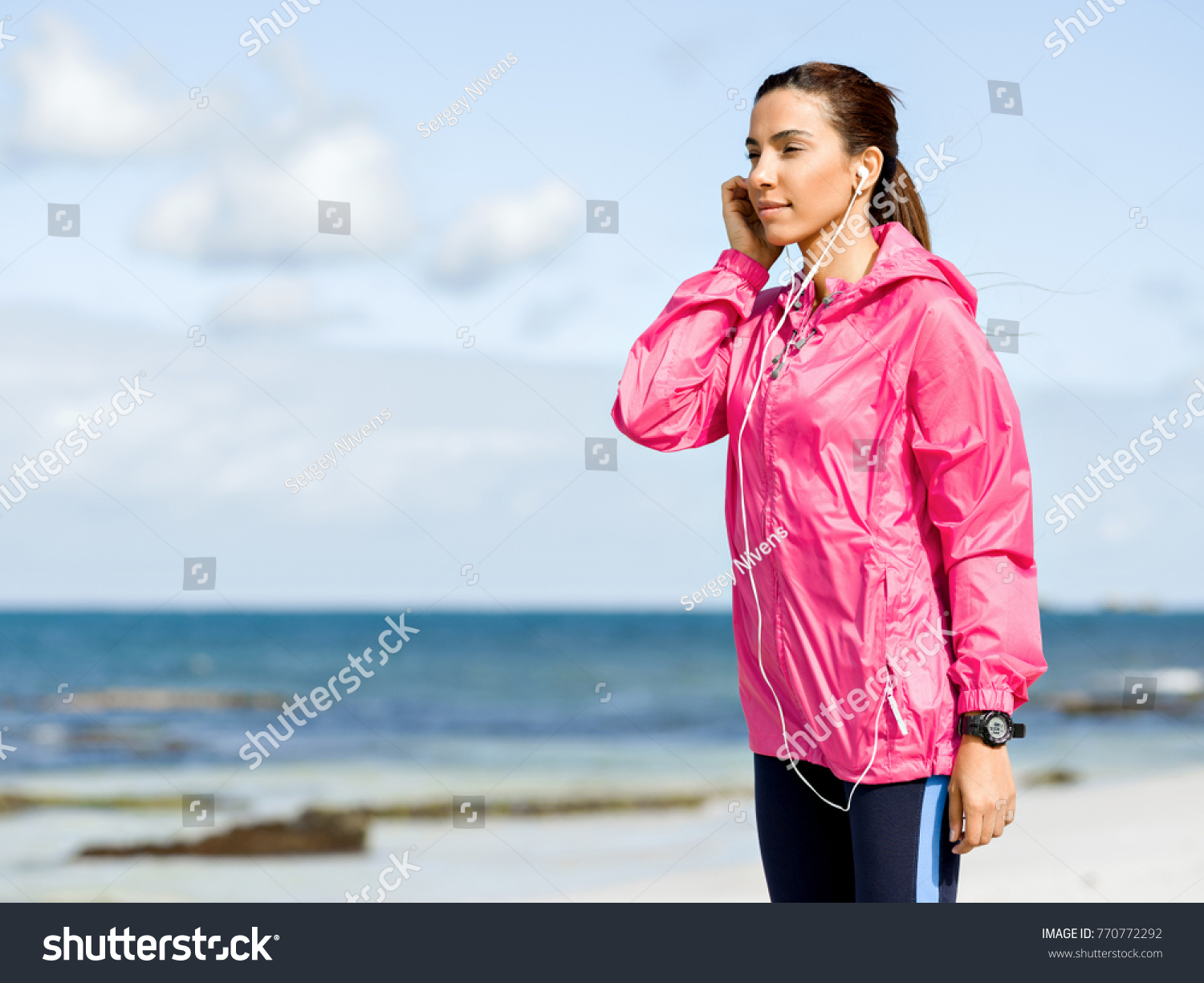 Sporty woman with earphones on the sea coast #770772292