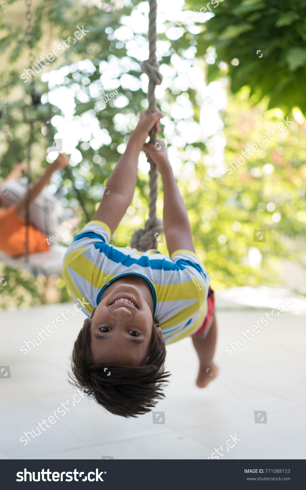 Cute happy little boy upside down on swing rope #771088153