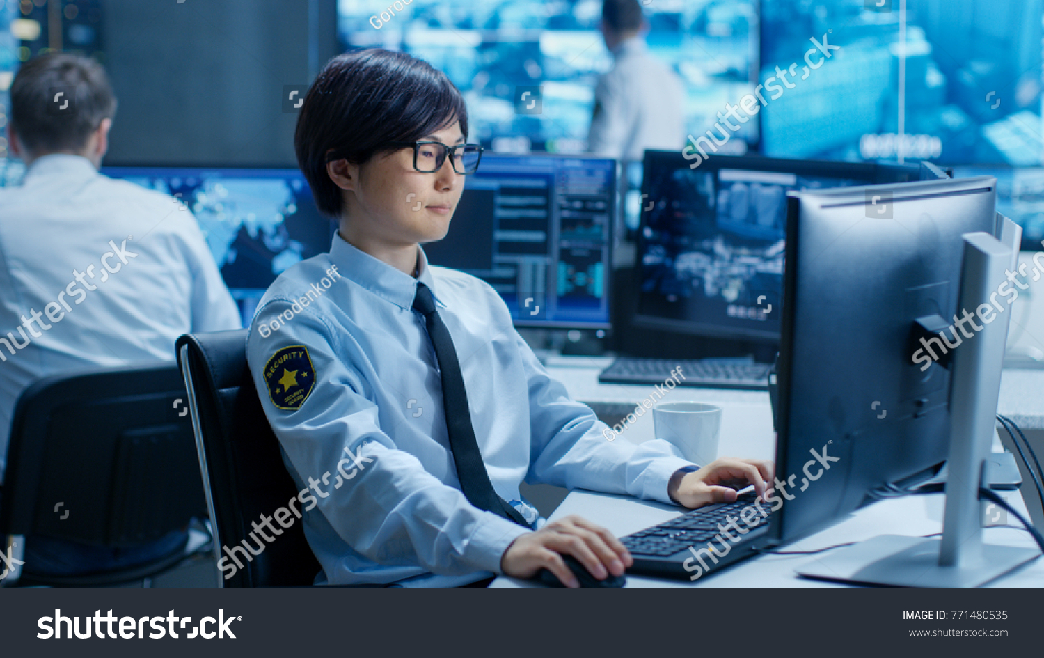 In the Security Command Center Officer at His Workstation Monitors Multiple Screens for Unlawful Infiltration. They're Guarding Important International Logistics Facility. #771480535