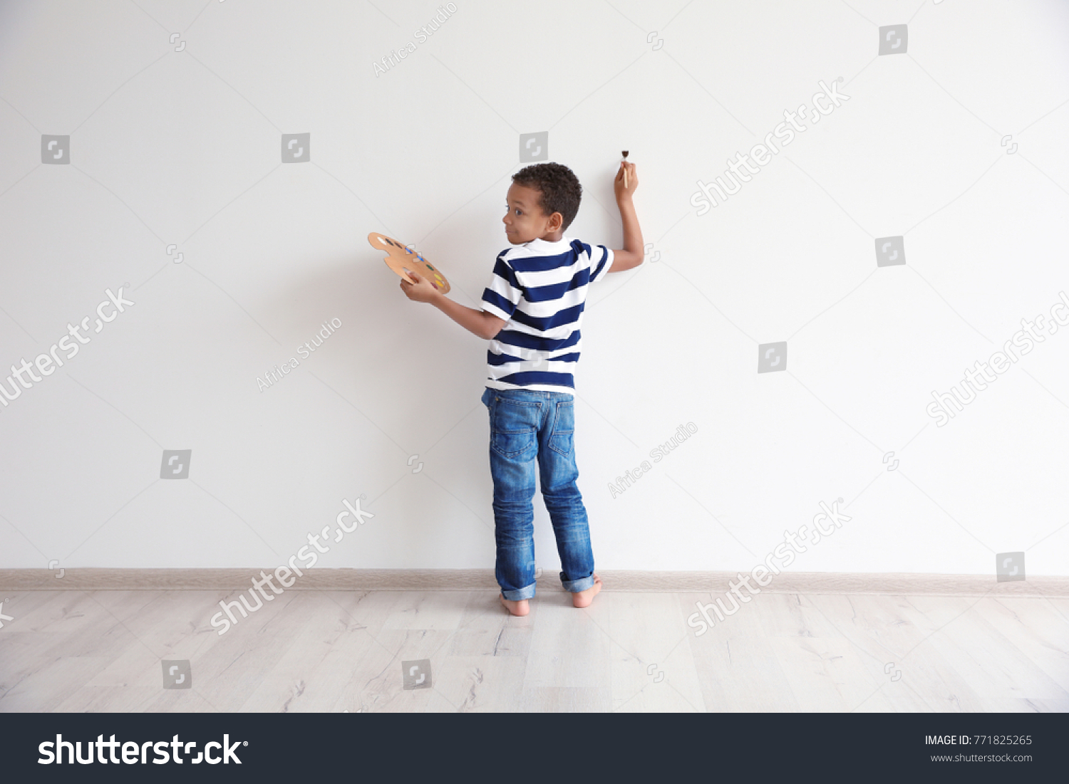 Little African-American boy painting on wall indoors #771825265