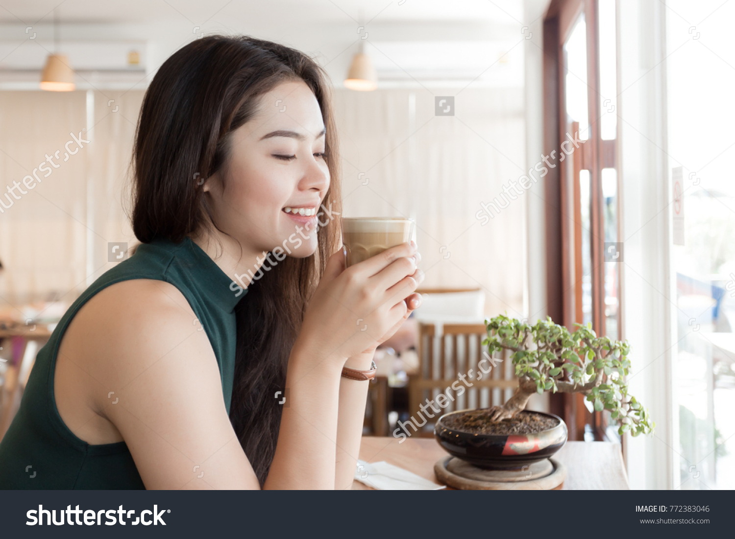 Young happy Asian woman drinking coffee in the coffee shop. #772383046