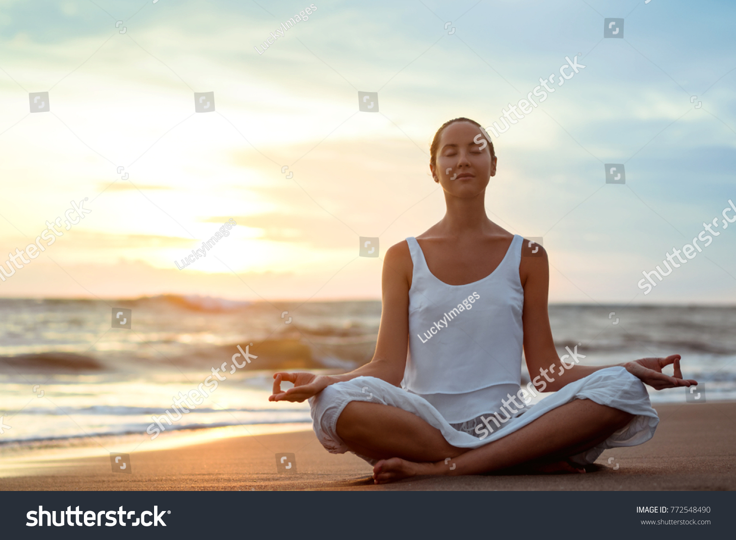 Young girl practicing yoga on the beach #772548490