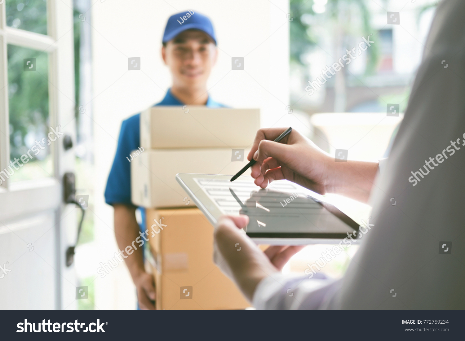 delivery, mail, people and shipping concept.Young woman sign in digital mobile phone after receiving parcel from courier at home. #772759234