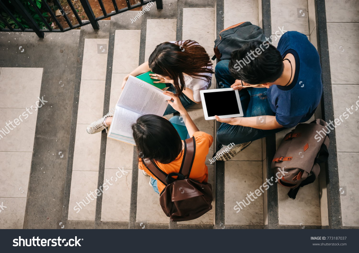 A group of young or teen Asian student in university smiling and reading the book and look at the tablet or laptop computer in summer holiday. #773187037