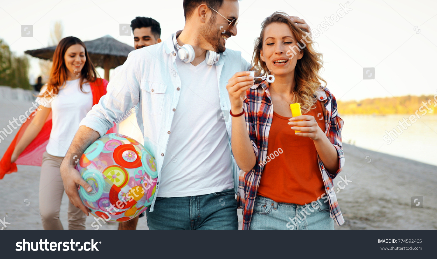 Beach party with friends. Cheerful young people spending nice time together on the beach #774592465