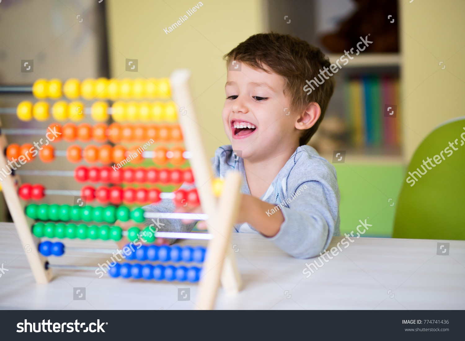 Happy kid playing with abacus toy at kindergarten. Adorable smart child learning to count. Early kids development. #774741436
