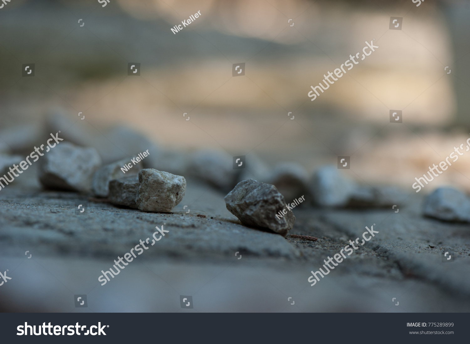 stones in the foreground and blur in the background, stones are light grey and the background grey and  orange colors, stones are in a group, the focus is on two stones and the others are blur  #775289899